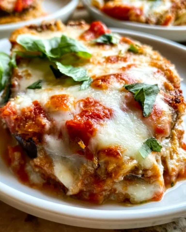 Crispy baked eggplant parmesan served with fresh basil on a plate